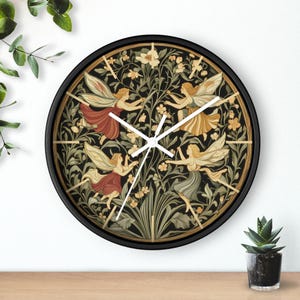 Puede incluir: Un reloj de pared con marco negro, esfera blanca y agujas blancas. La esfera del reloj presenta una ilustración vintage de hadas bailando en un jardín con flores y hojas.