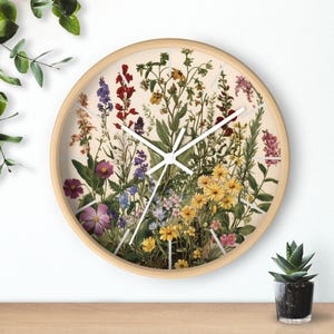 Könnte beinhalten: Eine runde Holzuhr mit weißem Zifferblatt und weißen Zeigern. Das Zifferblatt der Uhr zeigt ein farbenfrohes Blumenmuster mit verschiedenen Blumen und Blättern.