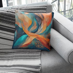 May include: A throw pillow with an abstract design featuring swirling colours of teal, orange, and gold. The pillow is on a grey sofa with a black and white striped throw blanket.