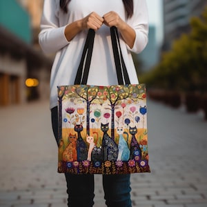 以下が含まれることがあります： 森の風景の中に猫たちが描かれた、カラフルなトートバッグ。猫たちは様々なポーズと色で描かれており、周りには花や木が描かれています。バッグは黒い持ち手と白い背景をしています。