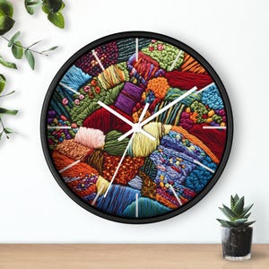 May include: A round wall clock with a black frame and white hands. The clock face is a colorful abstract design of stitched fabric in shades of red, blue, green, yellow, and purple.
