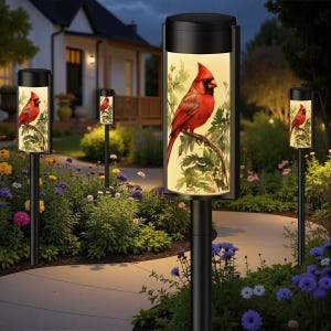 May include: Outdoor pathway lights with a black finish and a cylindrical design. Each light features a vibrant image of a red cardinal perched on a branch, set against a soft yellow background. The lights are placed along a garden path.