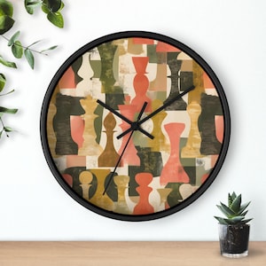 May include: Round wall clock with a black frame. The clock face features a colorful abstract design of chess pieces in shades of orange, green, and beige. The clock hands are black.