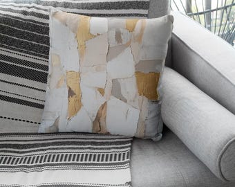May include: A gray couch with a black and white striped throw blanket and a white pillow with a gold and beige abstract design.