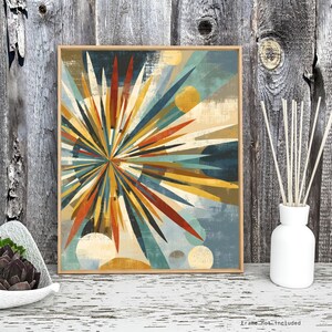 May include: Abstract art print in a wooden frame. The artwork features a burst of colorful geometric shapes in shades of blue, orange, yellow, and brown. The background has a textured, distressed appearance. The print is displayed on a white surface with a wooden background.