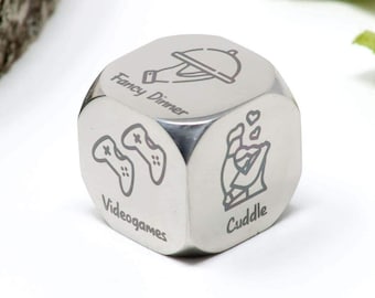 May include: A silver metal dice with six different activities engraved on each side: "Fancy Dinner", "Videogames", "Cuddle", "Movie Night", "Board Games", and "Date Night".