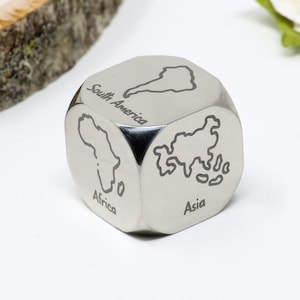 May include: A silver metal dice with continents engraved on each side. The continents shown are Africa, Asia, South America, North America, Europe, and Australia. The dice is a fun and educational way to learn about the world.
