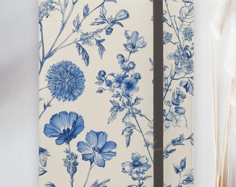 May include: A cream-colored notebook cover with a blue floral design. The cover features a repeating pattern of detailed blue flowers and foliage. A black elastic band secures the notebook. A red circle with "FAST DELIVERY" is in the upper left corner.