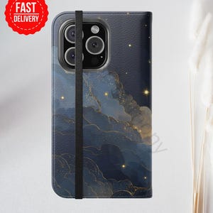 May include: A navy blue phone case with a celestial design featuring gold accents and a black elastic strap. The case has a textured appearance and a red "FAST DELIVERY" sticker.