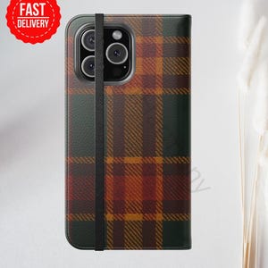 Op de afbeelding: Een telefoonhoesje met een ruitpatroon in bruin, oranje en groene tinten. Het heeft een zwarte bandsluiting en een rode sticker met de tekst "FAST DELIVERY".