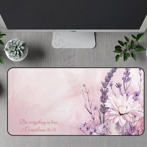 May include: A rectangular mousepad with a floral design in shades of pink and purple. The mousepad features a watercolor-style illustration of lavender and a large daisy. The text "Do everything in love. 1 Corinthians 16:14" is printed on the mousepad.