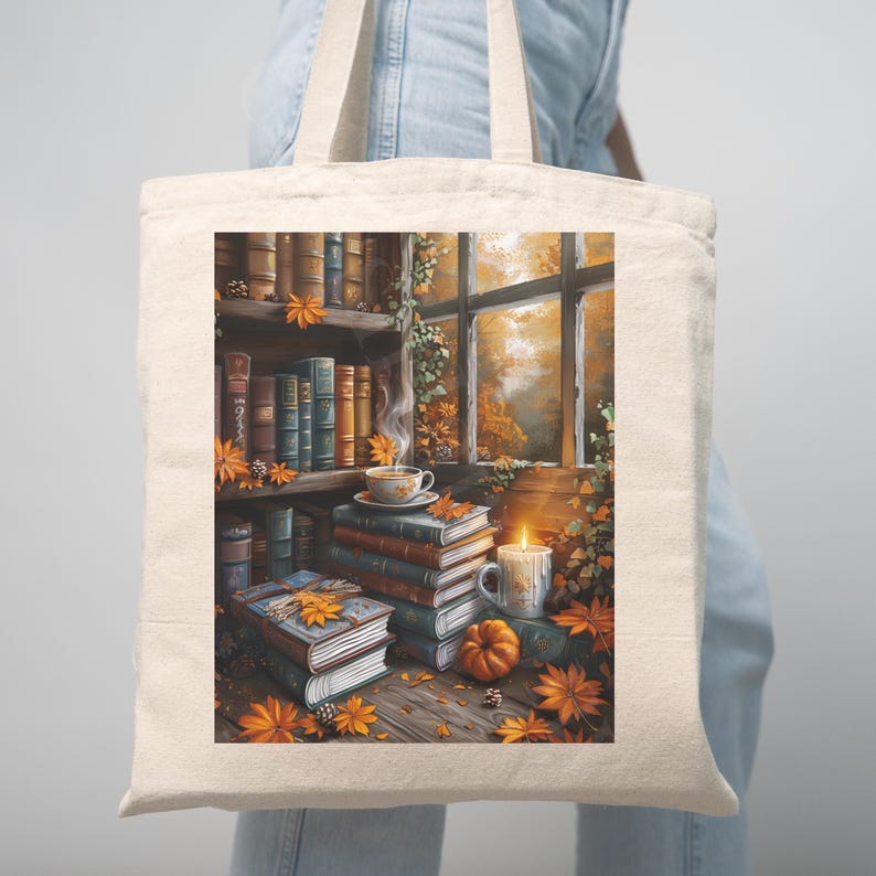 Cotton canvas tote bag featuring a cozy autumn library scene with stacked vintage books, a steaming coffee cup, glowing candle, pumpkins, and fall leaves by the window. Perfect gift for book lovers and cozy fall style