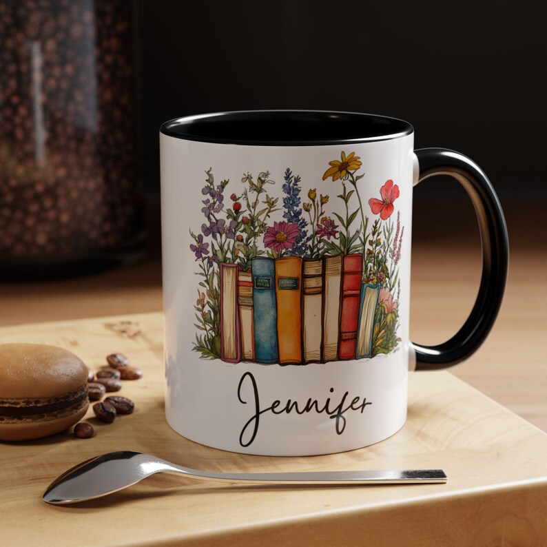 Personalized ceramic mug with black handle featuring a row of colorful books with blooming wildflowers and a custom name “Jennifer” in script – spiritual gift for readers and teachers.