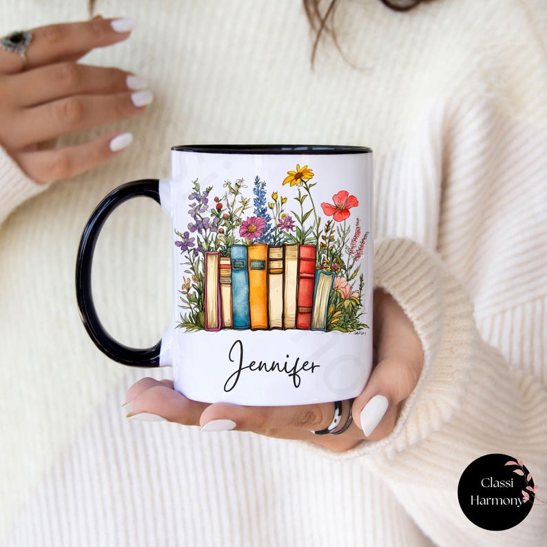 Personalized ceramic mug with black handle featuring a row of colorful books with blooming wildflowers and a custom name “Jennifer” in script – spiritual gift for readers and teachers.