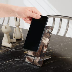 Pages, paper, soft shadows —
the kind of atmosphere that makes you slow down without trying.

This bookish phone stand brings a warm, vintage-inspired feel to your space, blending softly layered textures with a calm, grounded aesthetic.

Perfect for reading, writing, working — or simply creating a space that feels like your own.