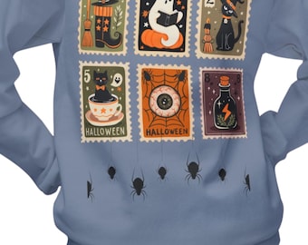 Può includere: Una felpa blu con disegni di francobolli a tema Halloween. I francobolli raffigurano un cappello da strega, un fantasma, un gatto nero e altri elementi spettrali. I ragni neri sono appesi nella parte inferiore della felpa.