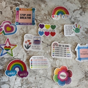 Könnte beinhalten: Ein Set aus 11 bunten Filzpatches mit Regenbogen-Designs und Texten zum Thema Atemübungen. Die Patches enthalten Sätze wie "Stop and Breathe", "Try to Find Things You Can See", "Smell the Flowers" und "Hold".