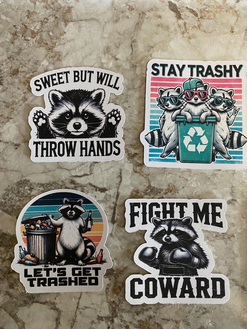 Puede incluir: Cuatro pegatinas con ilustraciones de mapaches y textos humor&iacute;sticos. Una dice "Sweet But Will Throw Hands". Otra dice "Stay Trashy" con mapaches con gafas de sol. Una tercera dice "Let's Get Trashed". La &uacute;ltima dice "Fight Me Coward."