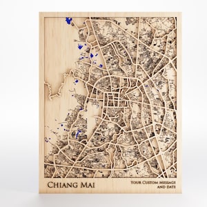May include: A wooden map of Chiang Mai, Thailand, with intricate laser-cut details. Blue accents highlight bodies of water. The text "Chiang Mai" and space for a custom message and date are at the bottom.