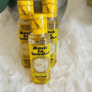 Könnte beinhalten: Drei gelbe Flaschen Back to Sender Parfümöl. Jede Flasche hat ein gelbes Etikett mit schwarzem Text, der "Back to Sender" und "Perfume" lautet. Die Flaschen stehen auf einer weißen, flauschigen Oberfläche.