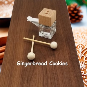 May include: A wooden diffuser bottle with a wooden lid and two wooden sticks. The bottle is filled with a clear liquid. The text "Gingerbread Cookies" is printed on a wooden surface.