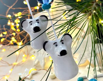 May include: Two white ceramic ornaments shaped like polar bears with black eyes and noses hanging from white strings with blue and clear glass beads.