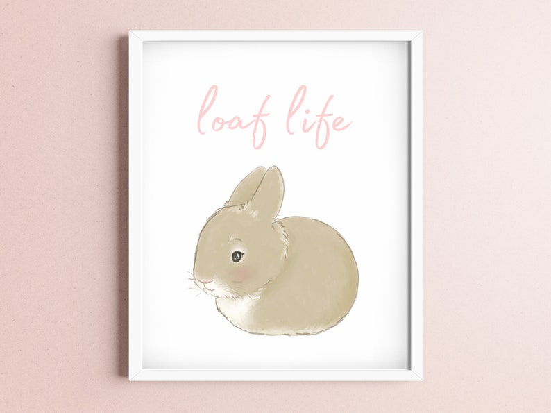 May include: A white framed print with a brown bunny sitting on a white background. The text "loaf life" is written in pink above the bunny.