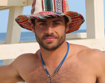 Puede incluir: Un sombrero de pescador de tela tejida multicolor con rayas verticales y horizontales en rojo, verde, blanco y negro. El sombrero tiene un ala ancha y flexible y un exterior texturizado con patrones. Un collar de cordón azul con un silbato negro.