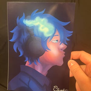 May include: An art print featuring a side profile of a person with blue hair and headphones. The artwork has a digital painting style with a dark background and the artist's signature "Shyolet" in the bottom right corner.