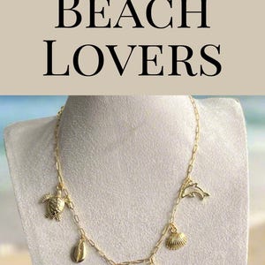 Puede incluir: Collar dorado con colgantes tem&aacute;ticos de playa, incluyendo una estrella de mar, una concha, una tortuga y un delf&iacute;n. El collar se exhibe en un maniqu&iacute;. Tambi&eacute;n se ve el texto "BEST GIFTS FOR BEACH LOVERS".