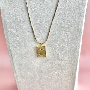 May include: A gold chain necklace with a small, ornate gold locket pendant.