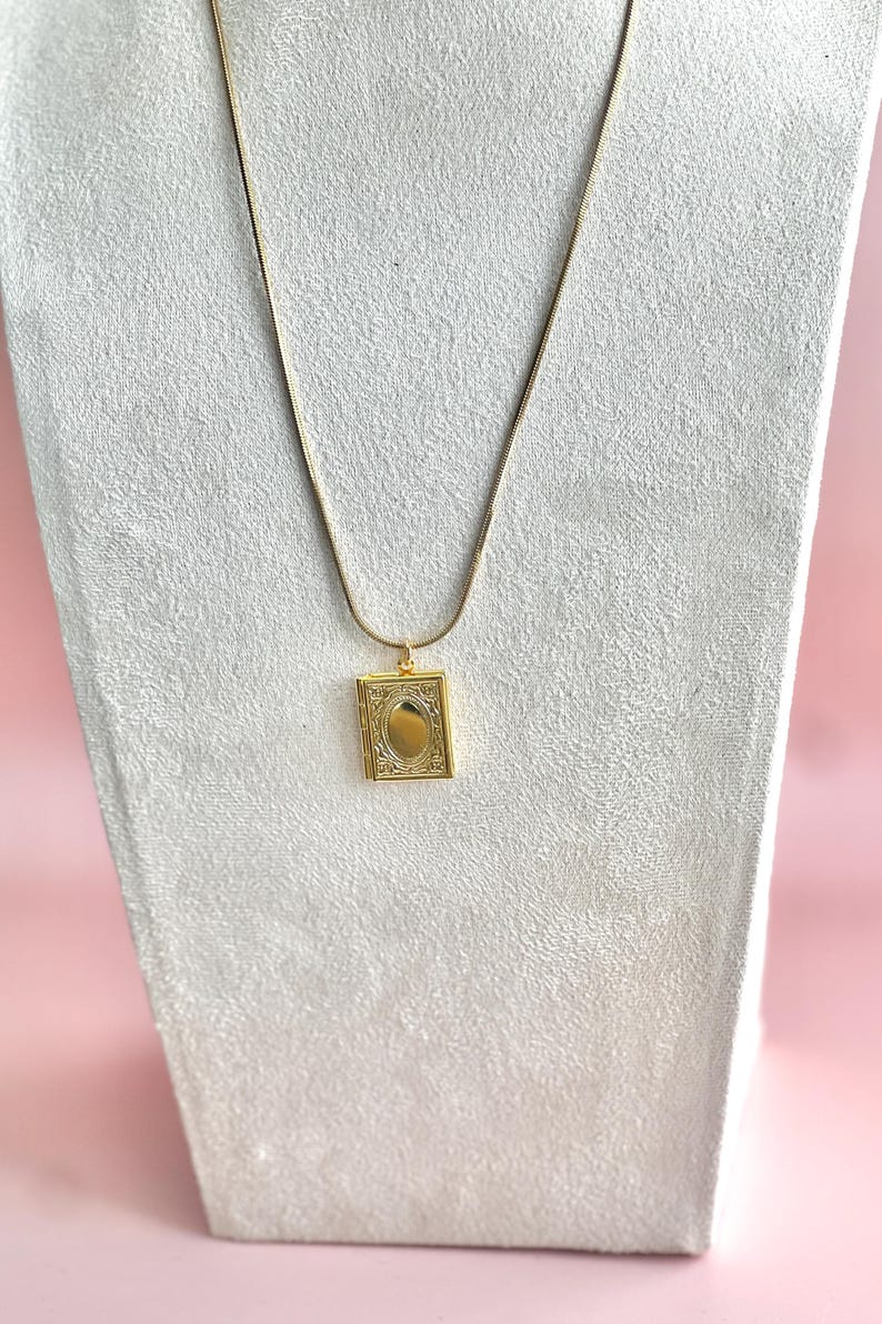 May include: A gold chain necklace with a small, ornate gold locket pendant.
