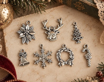 May include: A collection of seven silver-toned metal charms featuring holiday-themed designs including a poinsettia, a reindeer head, a Christmas tree, a bell, a snowflake, a wreath with a bow, and a candy cane, each with a small loop for hanging.