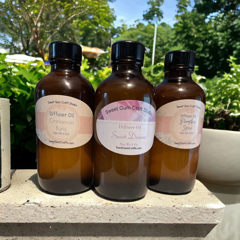 May include: Three brown glass diffuser oil bottles with black caps. Each bottle has a label with the text "Sweet Gum Craft Studio" and the scent name: Cinnamon Buns, Sweet Dreams, and Pumpkin Spice. Each bottle contains 118 ml of oil.