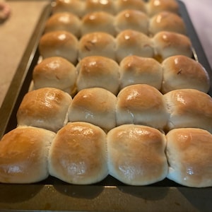 May include: A baking sheet filled with freshly baked, golden brown dinner rolls.
