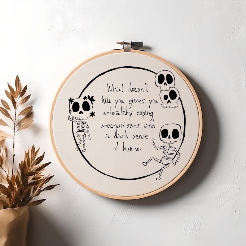 May include: Embroidered hoop art with a white background and black text that reads "What doesn't kill you gives you unhealthy coping mechanisms and a dark sense of humor". There are three black and white skeleton illustrations.