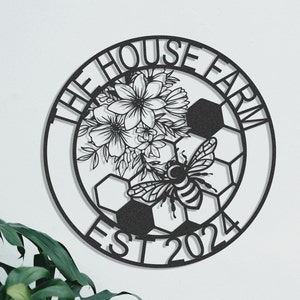 May include: Black metal wall art featuring a floral and bee design. The words "THE HOUSE FARM" and "EST 2024" are cut out in the metal. The design includes a soccer ball pattern.