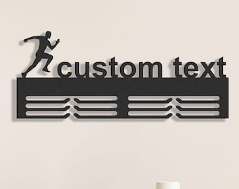 May include: Black metal running-themed wall art with the words "custom text". A silhouette of a runner is positioned above the text. Below the text are three horizontal bars with slots for displaying medals. A decorative item.