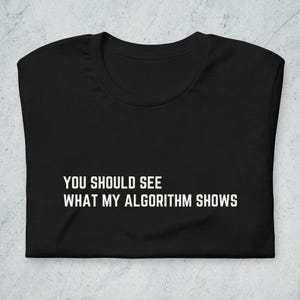 May include: Black t-shirt with white text that reads "You should see what my algorithm shows."