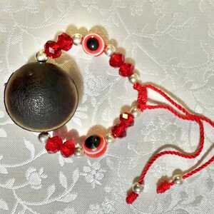 May include: Red and silver beaded bracelet with two blue and white evil eye charms. The bracelet has a red string tie closure.