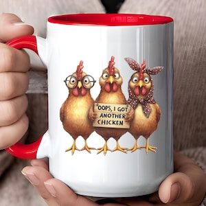 Puede incluir: Taza de cerámica blanca con interior y asa rojos, con una ilustración humorística de tres gallinas. Una gallina lleva gafas, otra sostiene un cartel que dice "Oops, I got another chicken."