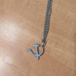 Puede incluir: Un collar de cadena de plata con un colgante de martillo y hoz de plata.