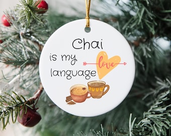 May include: White ceramic ornament with the text "Chai is my love language" in black script. A pink heart with an arrow is drawn through the word "love". Two mugs of chai are pictured below the text.