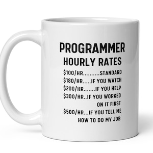 May include: White ceramic coffee mug with a black graphic that reads "PROGRAMMER HOURLY RATES $100/HR...STANDARD $180/HR...IF YOU WATCH $200/HR...IF YOU HELP $300/HR...IF YOU WORKED ON IT FIRST $500/HR...IF YOU TELL ME HOW TO DO MY JOB"