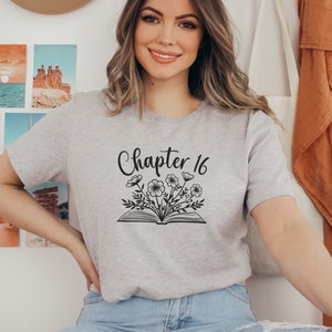 May include: A gray t-shirt with the text "Chapter 16" and a black and white illustration of a book with flowers on top.