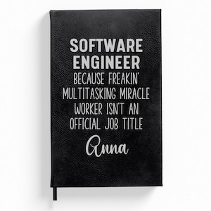 May include: Black leather-bound journal with the text "Software Engineer because freakin' multitasking miracle worker isn't an official job title Anna" in white lettering.