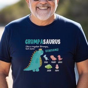 May include: A navy blue t-shirt with a graphic of a green dinosaur with a crown and the text "Grumpa-saurus Like a regular Grumpa, but more RAWESOME!"  Below the dinosaur are five smaller dinosaurs with the names Ryan, Mandy, Jimmy, Jason, and Poppy.