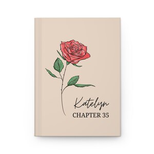 May include: A beige journal with a red rose illustration and green leaves. The journal cover features the name "Katelyn" in cursive script, with "CHAPTER 35" below it in a simple font.