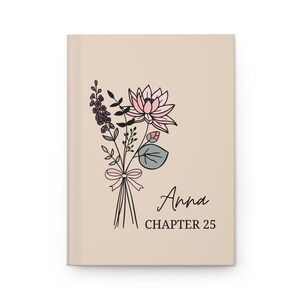 May include: A beige journal with a floral illustration and the text "Anna Chapter 25".
