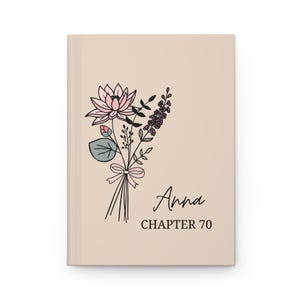 May include: A beige journal with a floral illustration and the text "Anna Chapter 70".